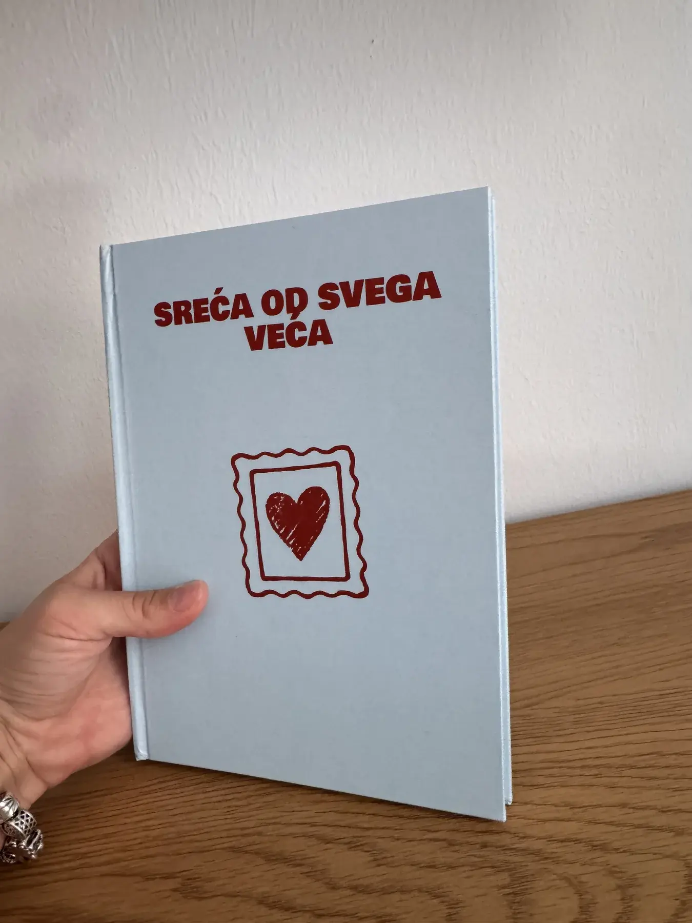 Stvarni svijetloplavi personalizovani foto album koji se drži u rukama