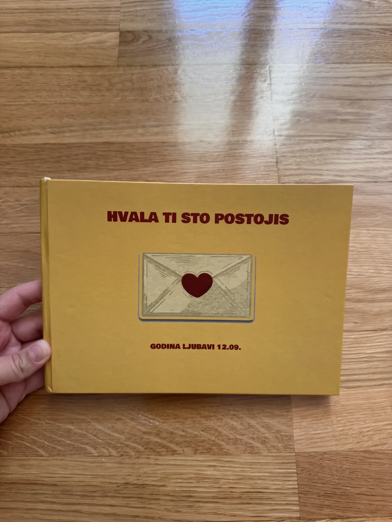 Stvarni žuti personalizovani foto album za godišnjicu na drvenoj podlozi
