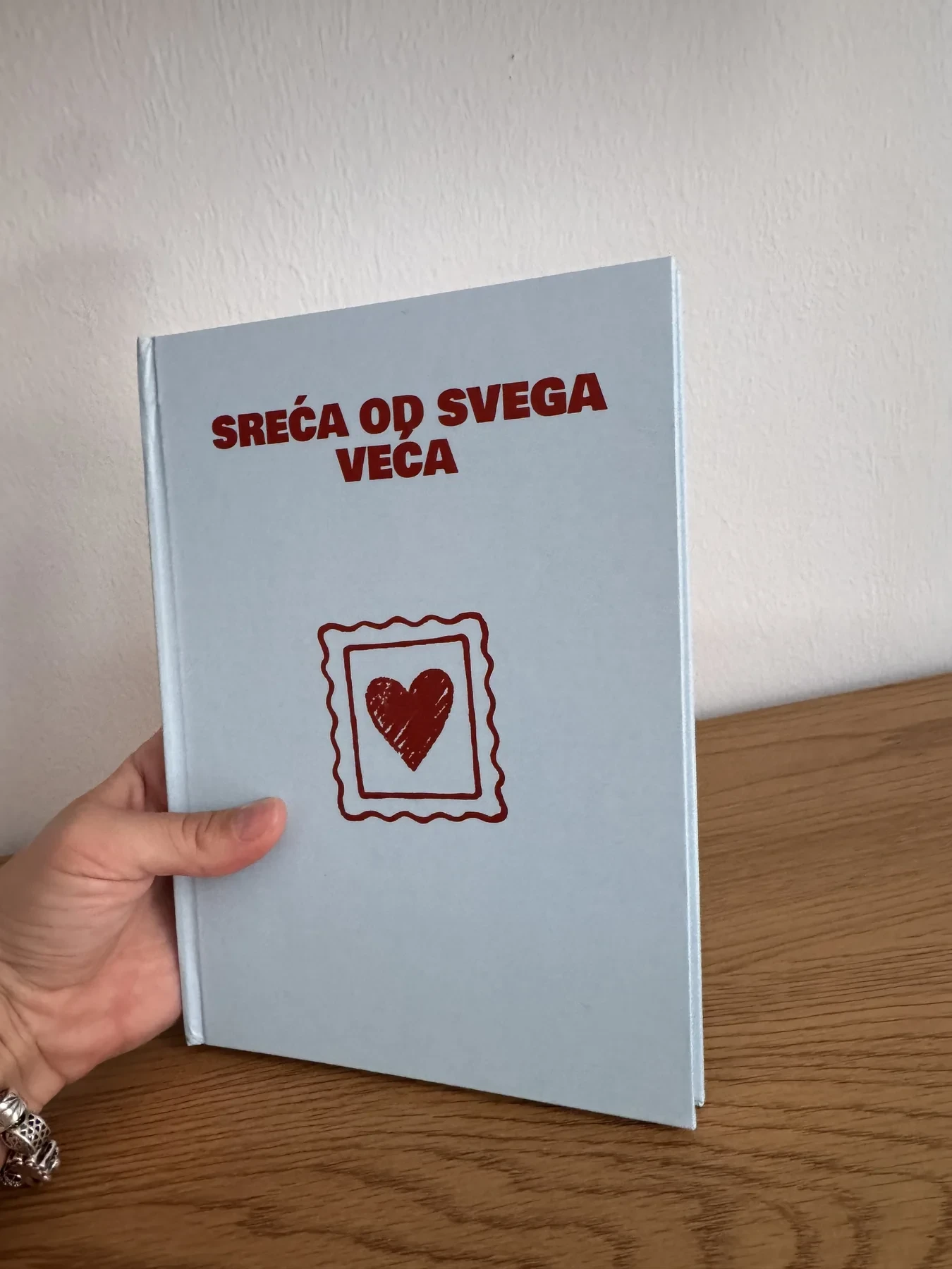 Stvarni svijetloplavi personalizovani foto album koji se drži u rukama
